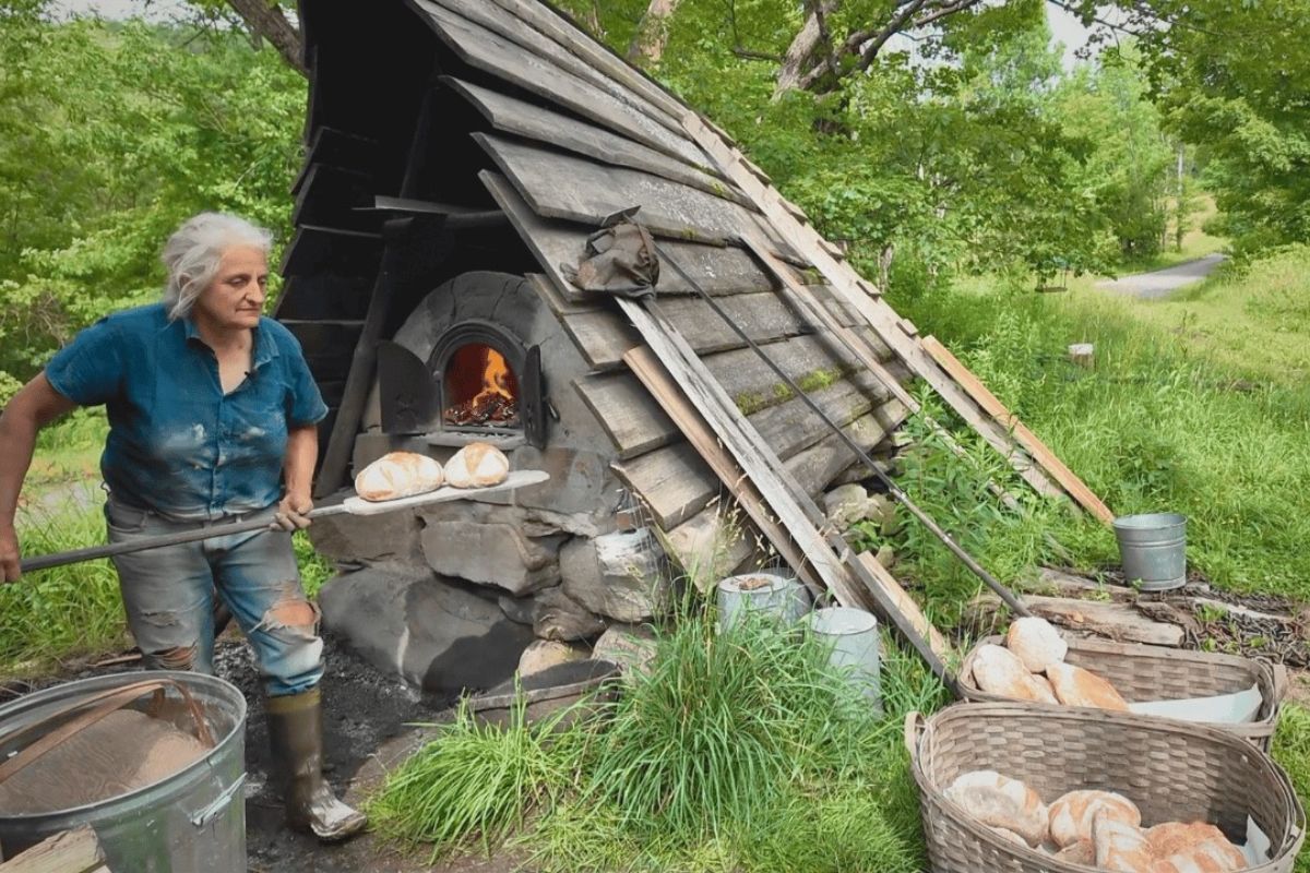 Mulher de 70 anos assa pão francês em forno de barro com cavalos de tração na Fazenda Harken, em Vermont, e sustenta famílias com vida autossuficiente.